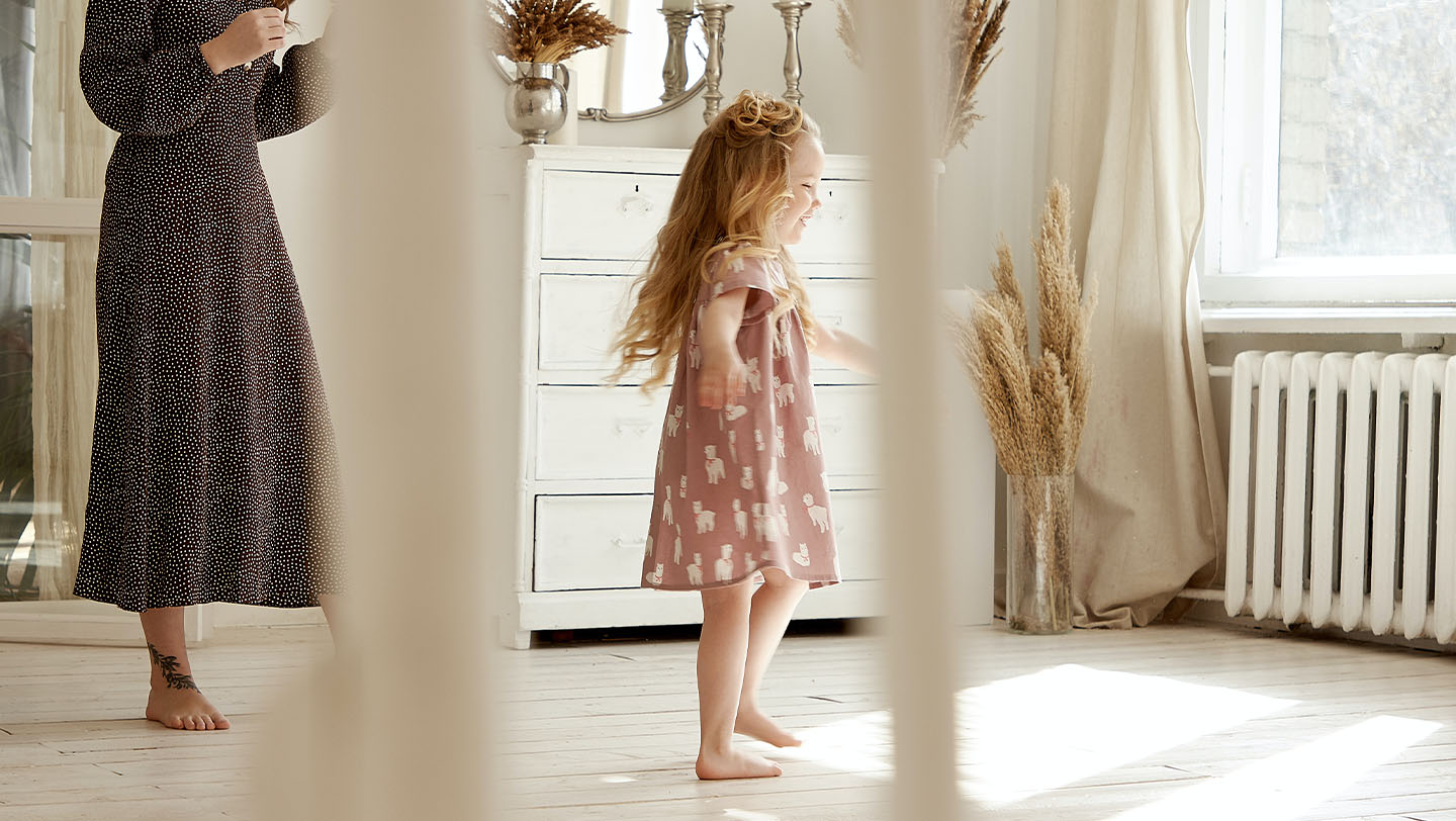 Pige danser foran vindue i et værelse.