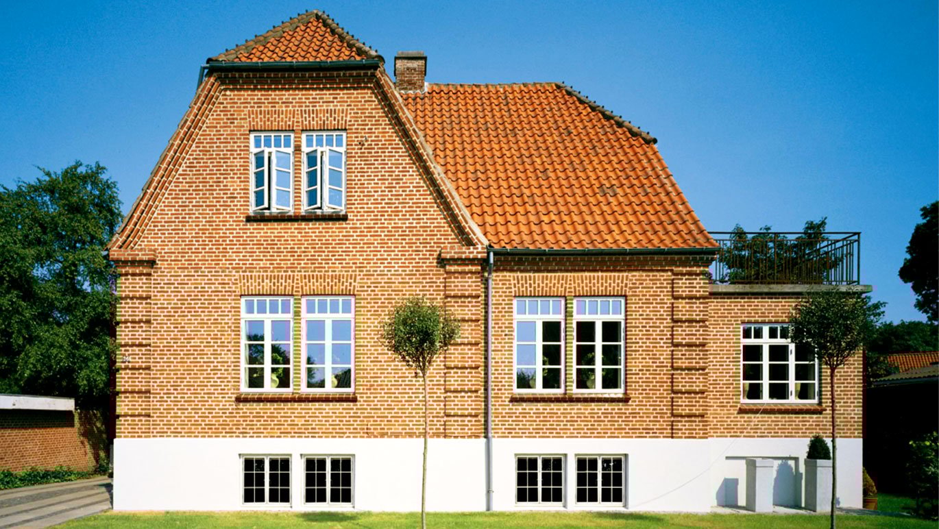 Rødt murstenshus med hvide sprossede vinduer.