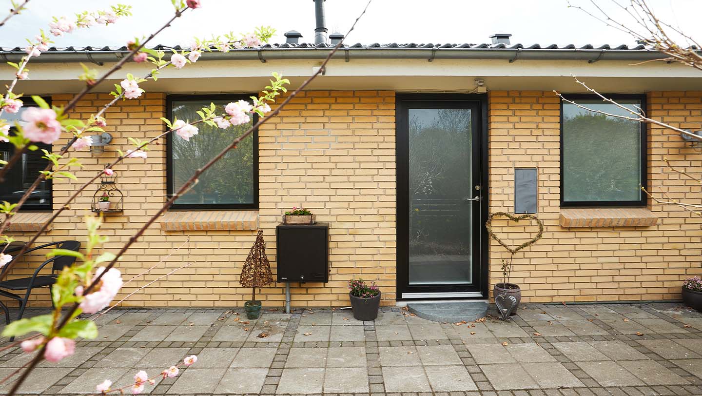 Hovedindgang med sort VELFAC facadedør på gul murstenshus.