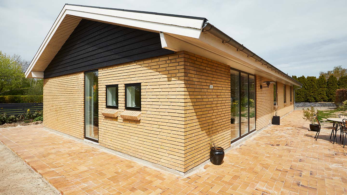 Facade på gult murstenshus, med sorte VELFAC vinduer.