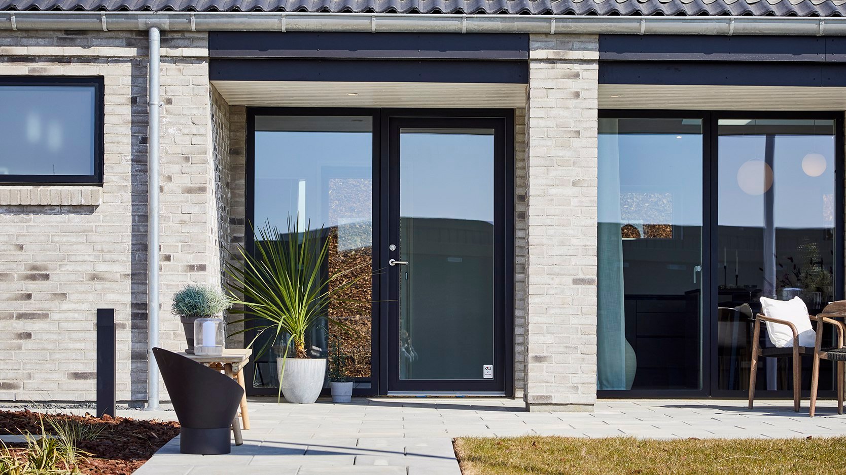 Facade med hvide mursten og sorte VELFAC 200 vinduer.