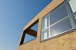 Mørke farver får vinduesrammen til at falde sammen med selve ruden og skaber en harmonisk overgang og ro i facaden
